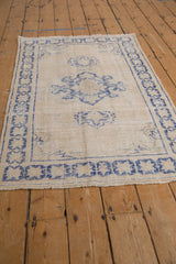 Distressed cobalt blue starburst border with ivory field and fringe on vintage Oushak rug.
