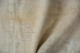 Distressed Oushak rug texture with visible knot heads, ivory, beige, and crease.