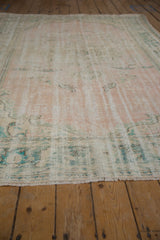 Worn pile texture of distressed Oushak carpet's pale pink and ocean green fringe.