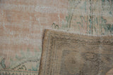 Distressed Oushak carpet pile in pale pink, ocean green, with its woven foundation.