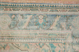 Distressed Oushak border detail with meandering vine motifs and pale pastel tones.