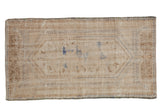 Distressed vintage Oushak rug with an elongated floral medallion in ivory, brown, and faded blue.