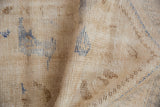 Distressed pile texture of a vintage Oushak rug, showing ivory, pale coffee brown, and thin blue lines.