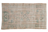 Hand-knotted distressed vintage Oushak rug with elongated floral medallion in ivory, seafoam, beige.