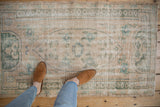 Distressed vintage Oushak rug with faded seafoam green floral motifs, serpent border, even wear.