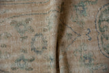 Detail of vintage Oushak rug showing mostly even wear, exposed foundation, and green motifs.
