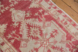 Distressed vintage Oushak rug detail showing even wear, faint foundation, dusty raspberry and beige.