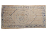 Distressed vintage Oushak rug featuring ivory field, deep denim blue roundel, and vine borders.
