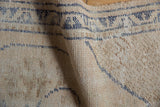 Distressed vintage Oushak rug's textured wool pile with beige and dusty denim blue lines.