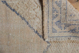 Close-up of distressed Oushak rug pile, folded to reveal hand-knotted foundation and short fringe.
