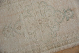 Worn ivory and beige Oushak rug pile, with subtle seafoam green motifs and visible foundation.