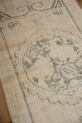 Distressed vintage Oushak runner, showing muted ivory-beige ground and visible knot head wear.