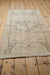 Distressed vintage Oushak rug's ivory roundel medallion, beige ground, oxidized silver outlines.