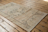Distressed vintage Oushak rug corner showing low pile, oxidized silver rams horn, intact selvage.