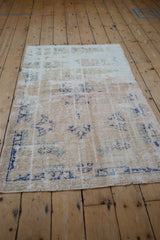 Distressed Oushak rug detail, highlighting visible foundation and worn texture in ivory, beige, denim blue.