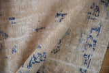 Textured surface of a distressed Oushak rug, revealing ivory foundation and denim blue patterns.