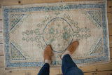 Distressed ivory Oushak rug featuring blue roundel medallion and seafoam green scrolling.