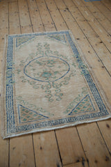 Distressed vintage Oushak rug corner with blue geometric border and scrolling ornamentation.