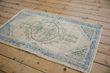 Distressed vintage Oushak rug corner, deep denim blue lattice border with scrolling green accents.
