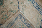 Vintage Oushak rug corner showing worn pile and deep denim blue geometric border.