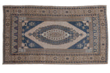 Distressed Oushak carpet with elongated medallion, geometric motifs in antique ivory and dusty denim blue.