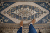 Textured distressed Oushak rug, faded dusty denim blue and antique ivory elongated medallion.