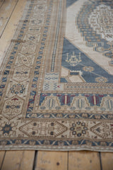 Distressed Oushak carpet corner with stylized lanterns in dusty blue and ivory.