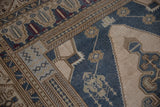 Distressed vintage Oushak rug close-up, dusty denim blue and beige geometric patterns with visible wear.