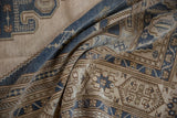 Distressed Oushak carpet folds reveal faded denim blue and beige geometric patterns.