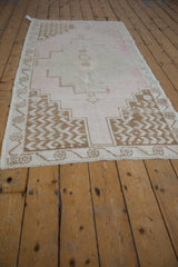 Distressed vintage Oushak rug corner: pale pink field, deep dusty bronze stepped border.