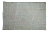 Vintage distressed Oushak carpet with a faded medallion pattern in pale dusty rose, ivory, and sea foam green.
