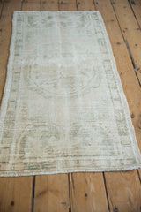 Distressed vintage Oushak runner with worn ivory and dusty olive green pile, foundation visible.
