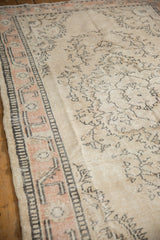 Distressed Oushak carpet detail, showing worn ivory field, charcoal floral motifs, and peach border.