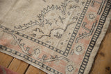 Distressed Oushak rug corner showing low pile, faint foundation, peach and charcoal borders.