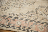 Distressed Oushak rug with low pile, showing ivory field and peach geometric border.