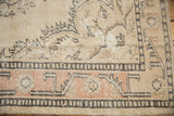 Distressed Oushak rug detail, peach border, charcoal geometric patterns, worn with foundation showing.
