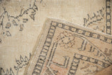 Distressed Oushak carpet corner with even wear on ivory pile and woven underside.