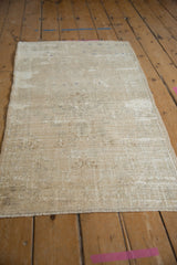 Distressed Oushak rug corner, highlighting worn texture, abrash, and visible foundation in ivory.