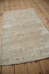 Distressed texture of a vintage Oushak rug with faded ivory, coffee, and faint navy blue specks.