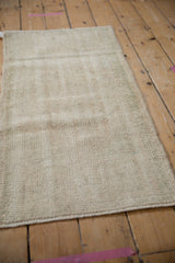 Textured close-up of distressed ivory Oushak rug runner, showing wear to foundation.