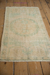 Distressed vintage Oushak rug pile with mostly even wear and faded green motifs.
