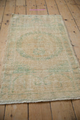 Distressed vintage Oushak rug pile texture showing faded ivory and sea foam green pattern.