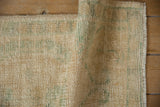 Close-up of distressed Oushak rug showing low pile texture in ivory and sea foam green.
