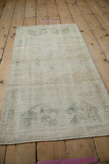 Textured ivory Oushak runner with beautifully distressed pile and faded green patterns.