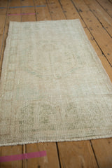 Worn texture and faded ivory, pale green shades of a distressed Oushak rug.