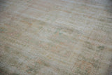Distressed texture of vintage Oushak carpet with soft pale rose and mint green tones.