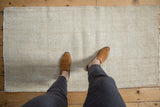 Distressed vintage Oushak rug with ivory tone-on-tone texture, wear, and feet.