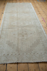 Faded geometric diamond motifs and visible foundation on a distressed Oushak runner.