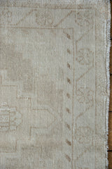 Distressed Oushak rug runner side edge, showing worn ivory beige pile and visible foundation.