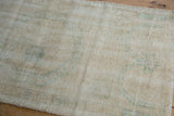 Distressed textured ivory pile of vintage Oushak rug runner with visible knot heads and faint green.